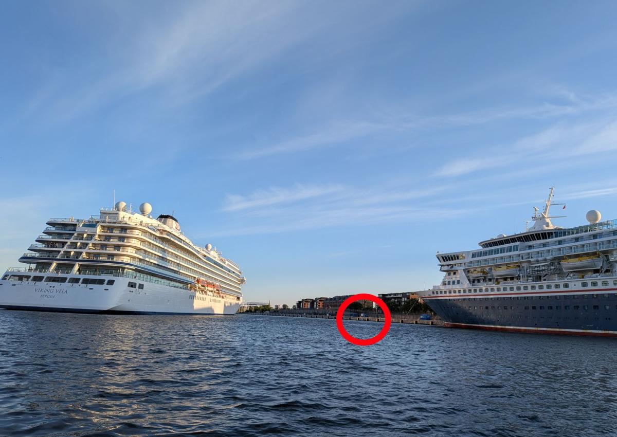 To store krydstogtskibe, en af dem er i gang med a lægge af. En lille jolle imellem dem er markeret med en rødt kreds.